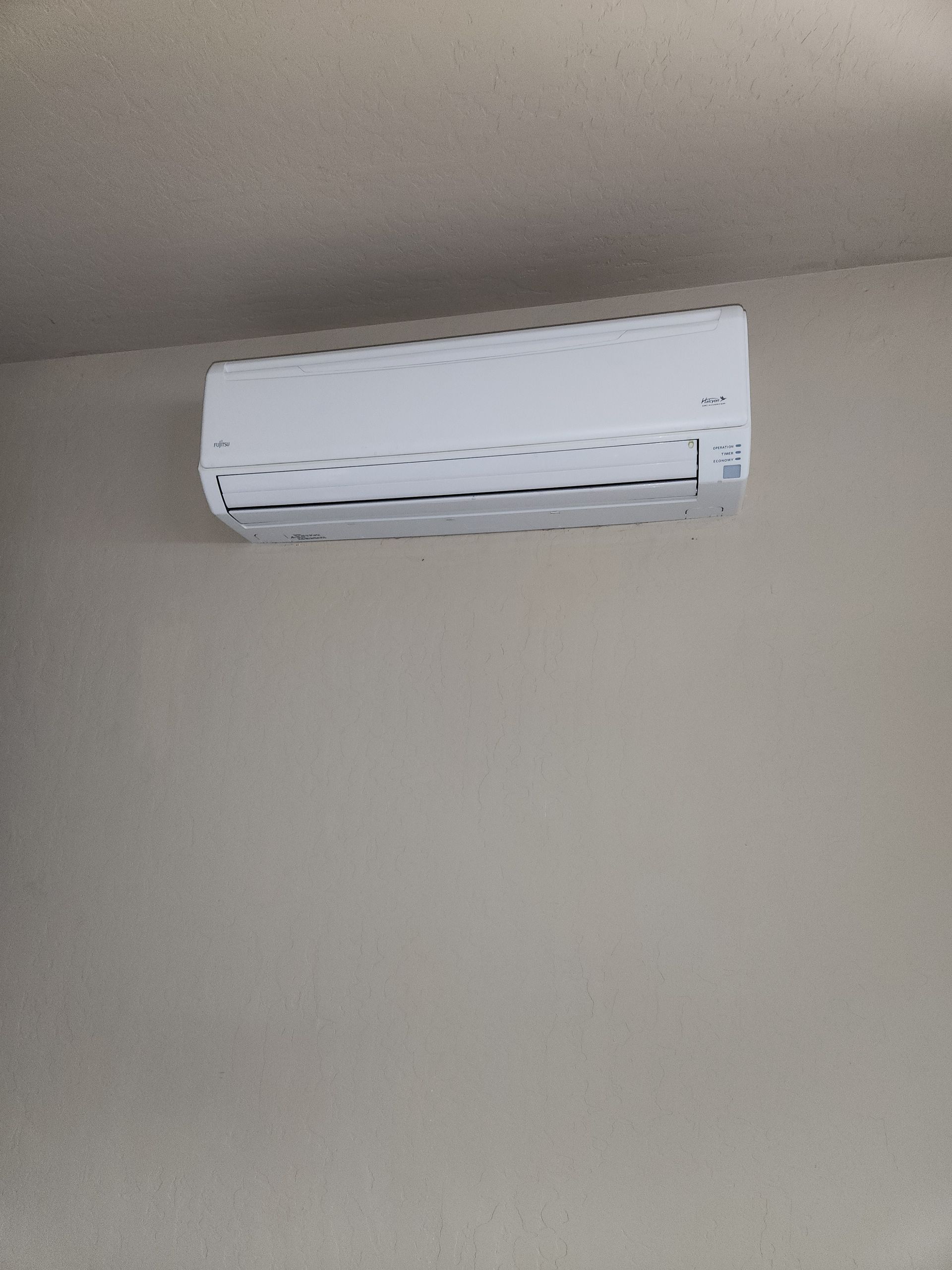 White wall-mounted air conditioner on a beige wall.