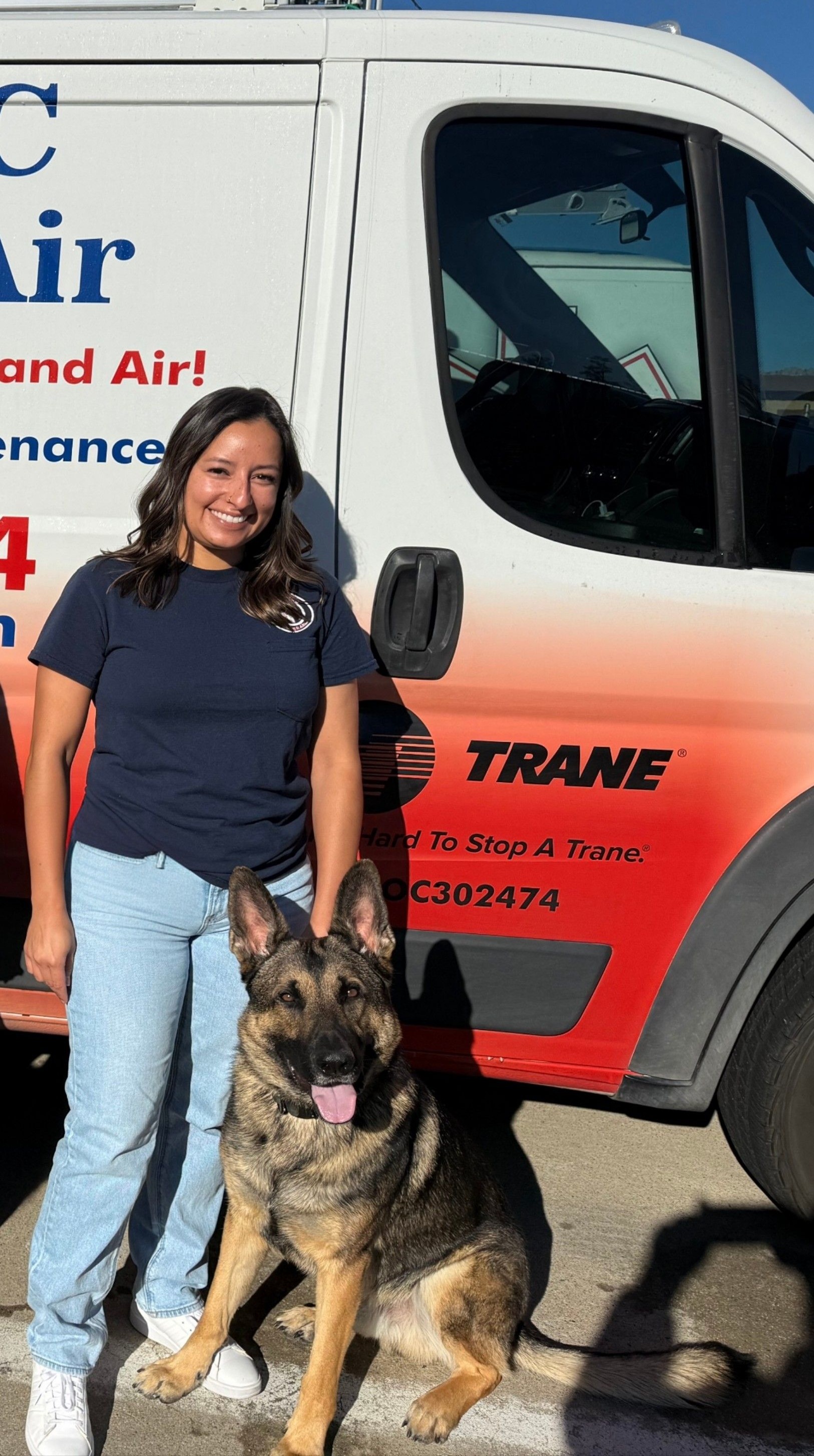 Woman with dark hair smiles, wearing a navy shirt. There's a tattoo on her arm.