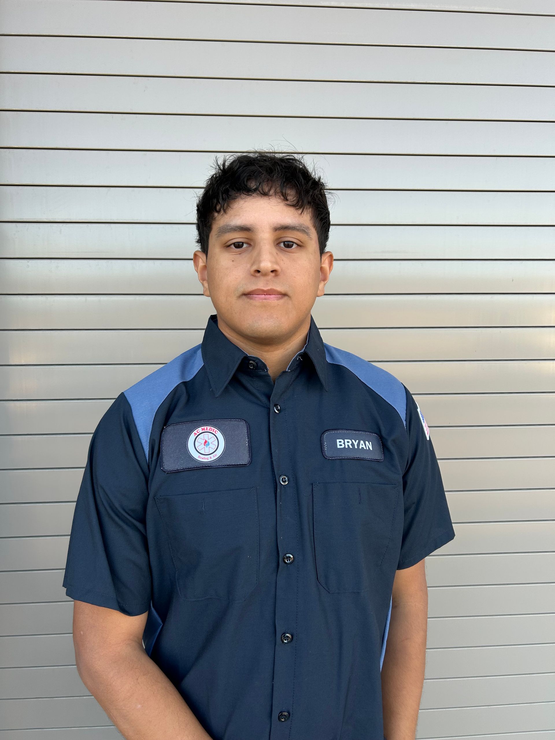 Person in a navy blue work shirt, standing in front of a corrugated metal wall.