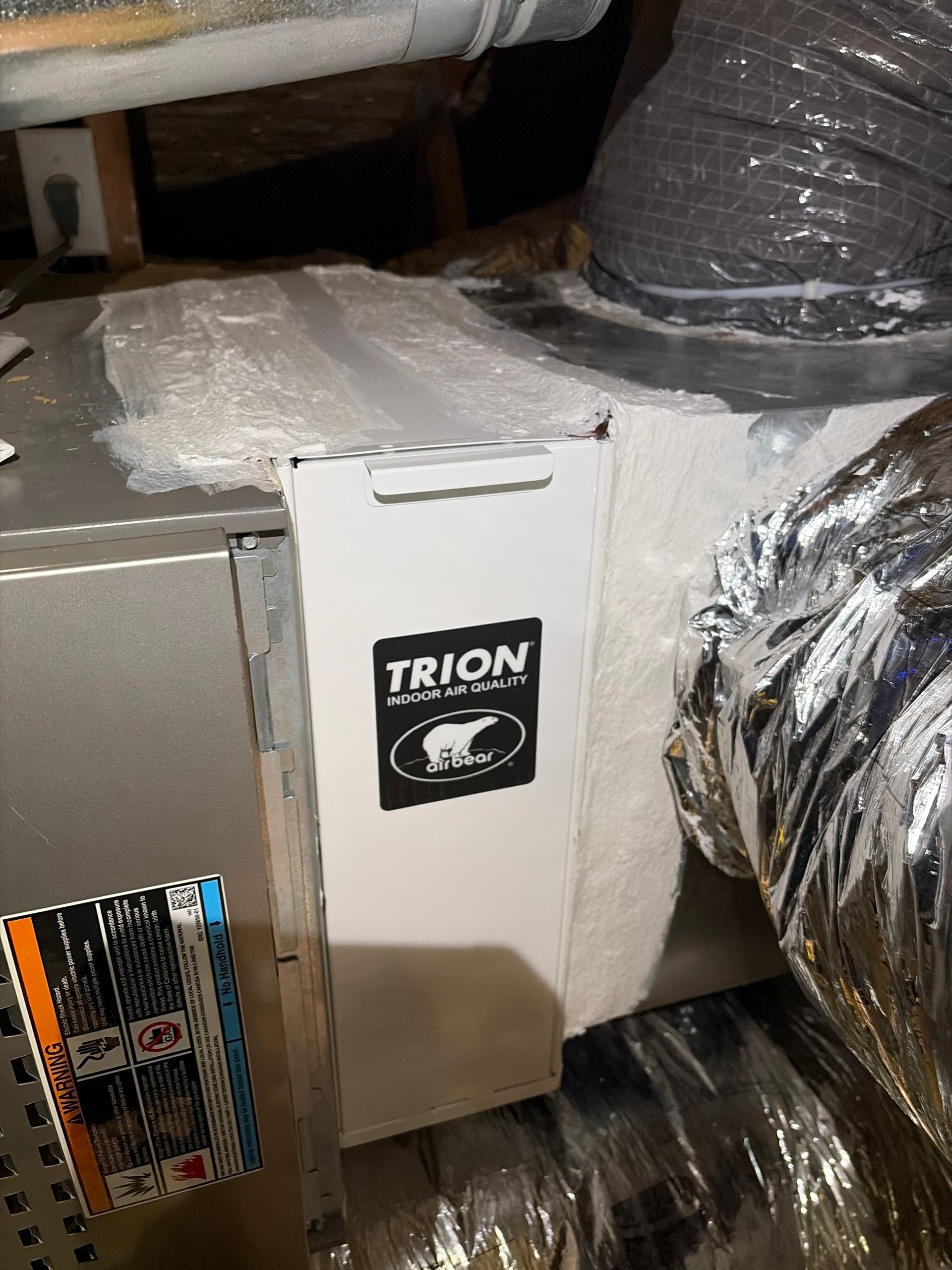 HVAC system with a Trion air cleaner box, insulated ductwork, and metal components in an attic space.