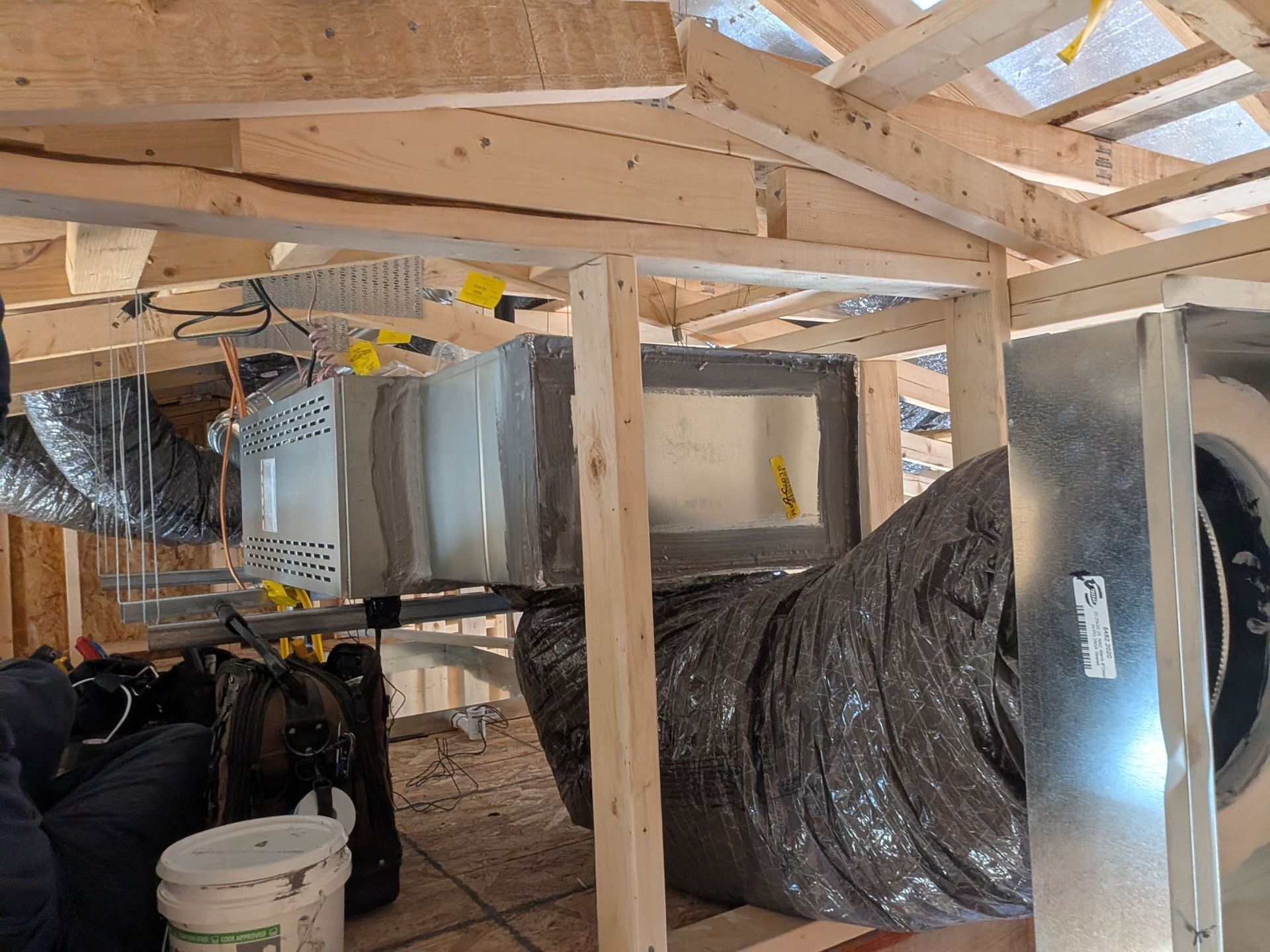 HVAC system components installed in unfinished wooden attic space. Ductwork, framing, and insulation visible.