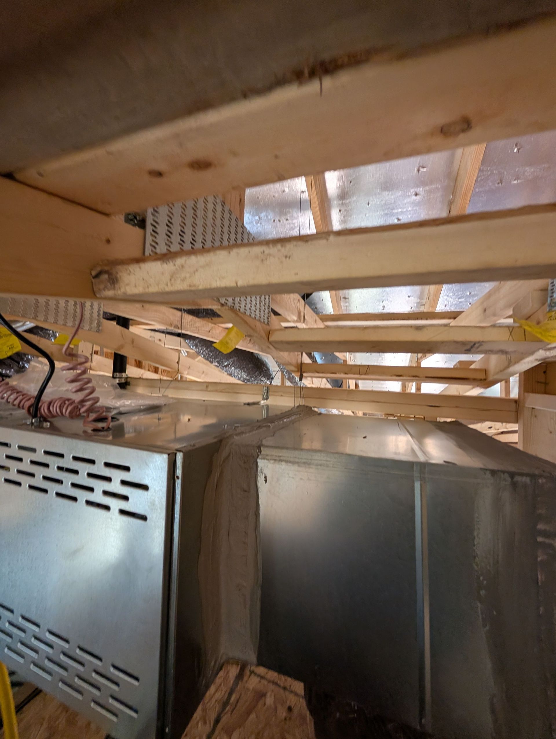 Overhead view of a metal appliance and ductwork in a wooden frame.