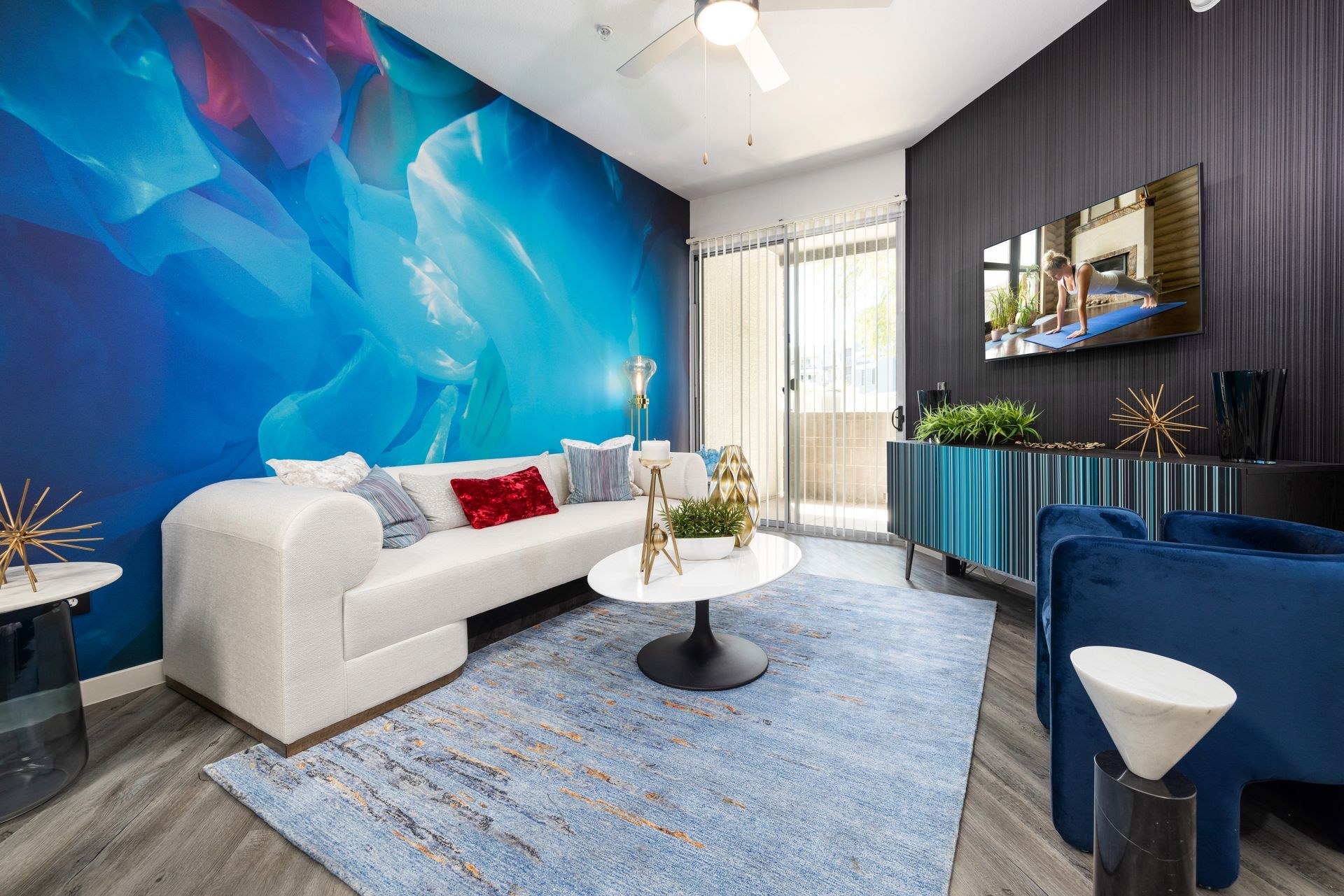 Living room with blue abstract mural, white sofa, blue rug, and dark walls.