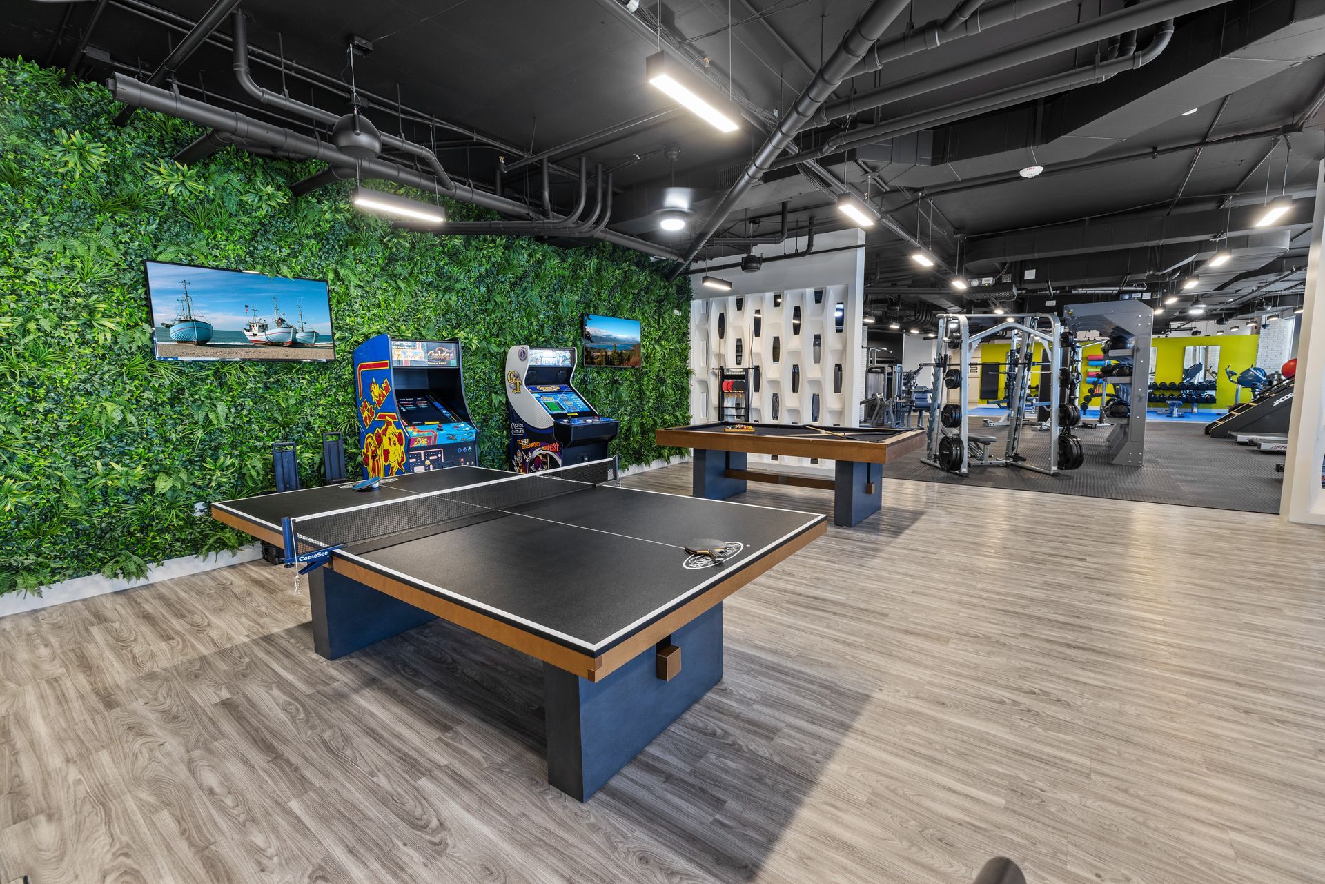 Game room with ping pong table, arcade games, and gym equipment; green wall.