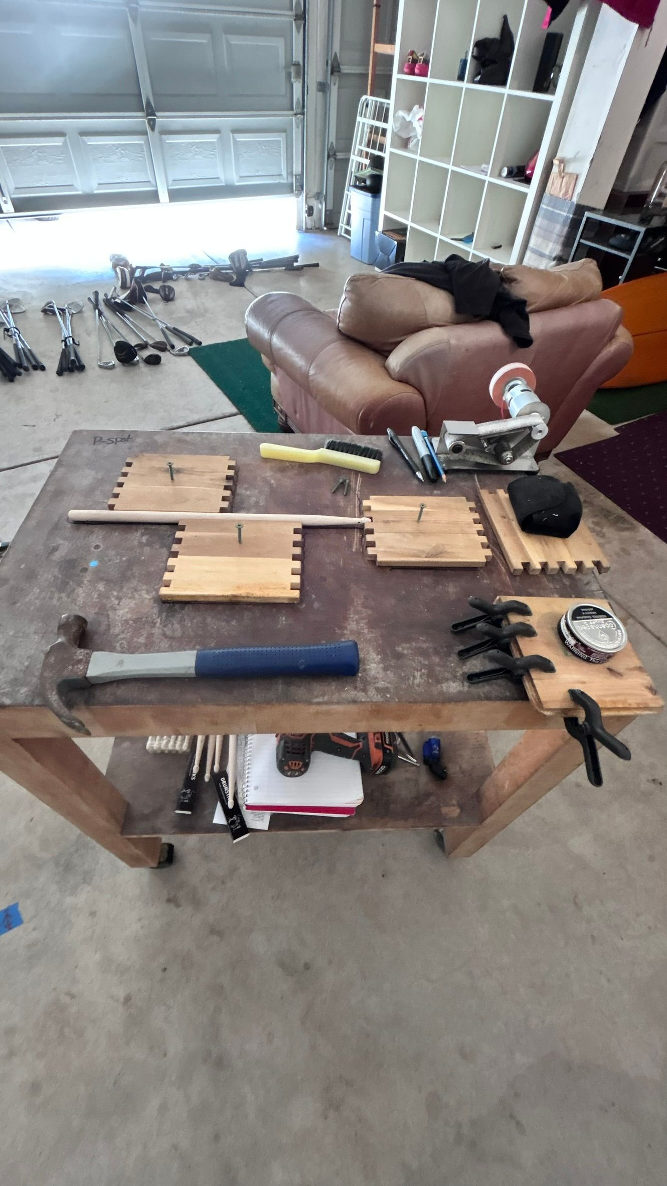 Woodworking workbench with dovetail joints being assembled, tools and parts visible in a garage.