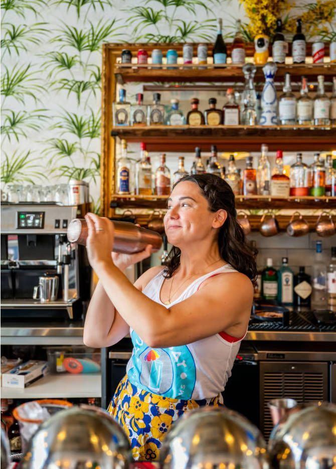 A woman is shaking a drink in a bar.