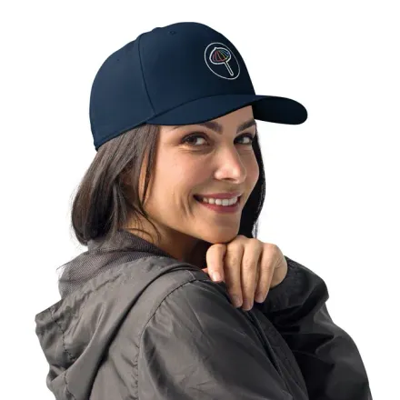 Woman wearing a navy blue cap with a logo, smiling, looking over her shoulder.
