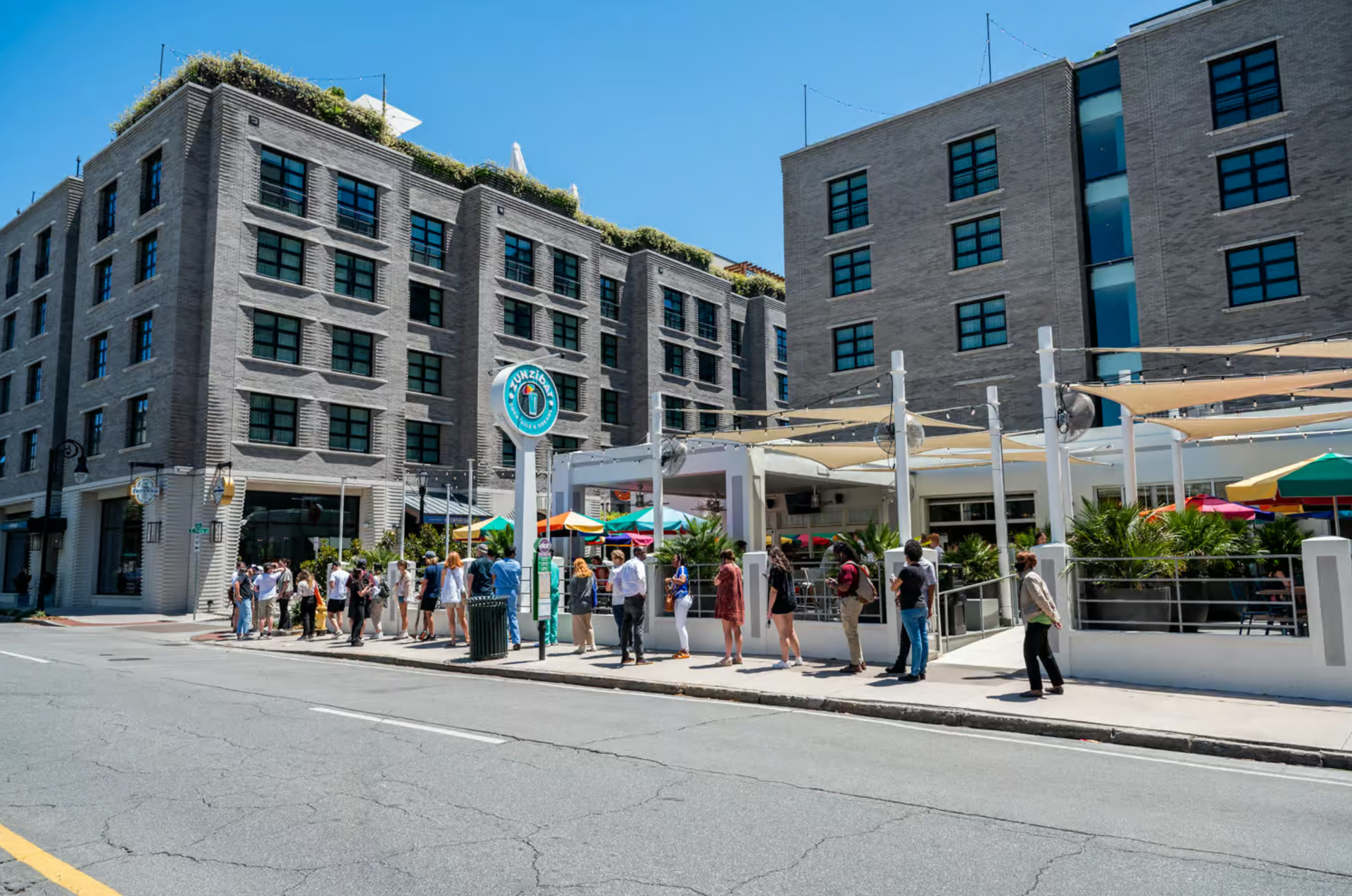 A group of people are standing on the sidewalk in front of a building.