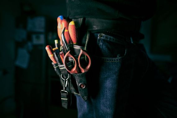 A person is wearing a tool belt with tools in it.