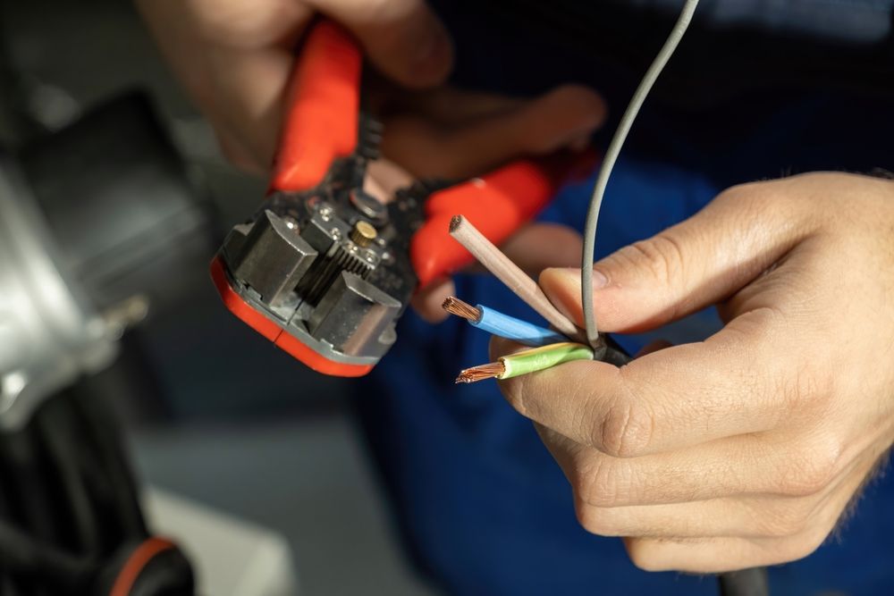 A person is cutting a wire with a pair of pliers.