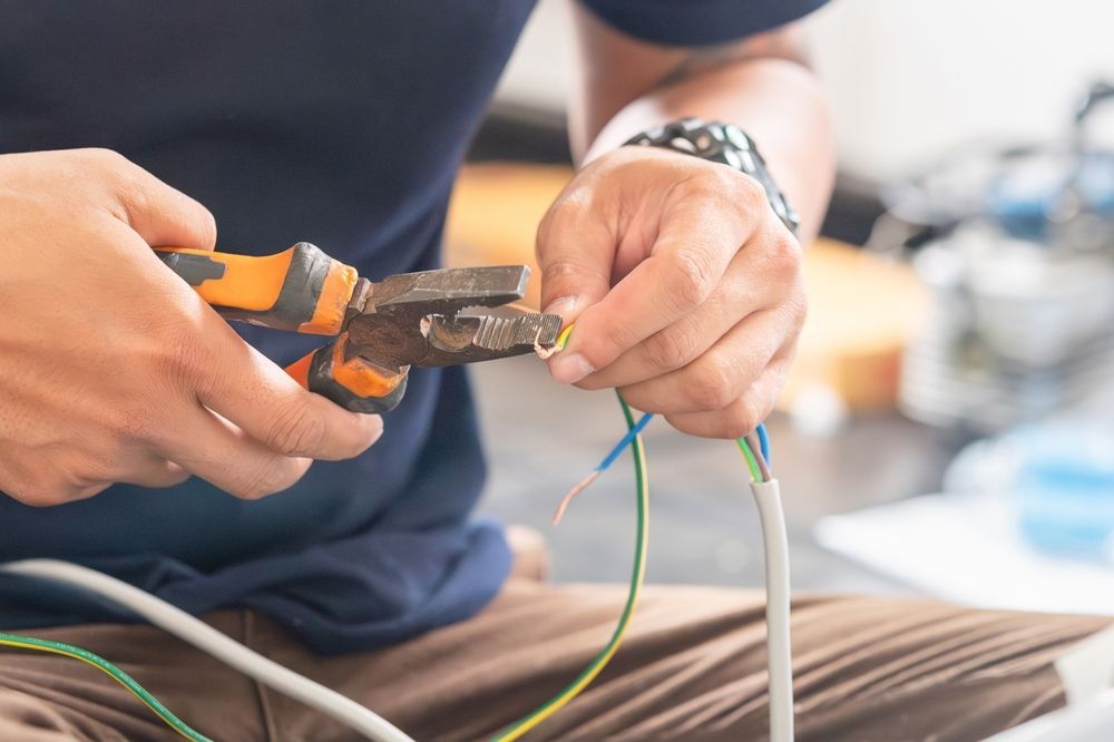 A man is cutting a wire with a pair of pliers.