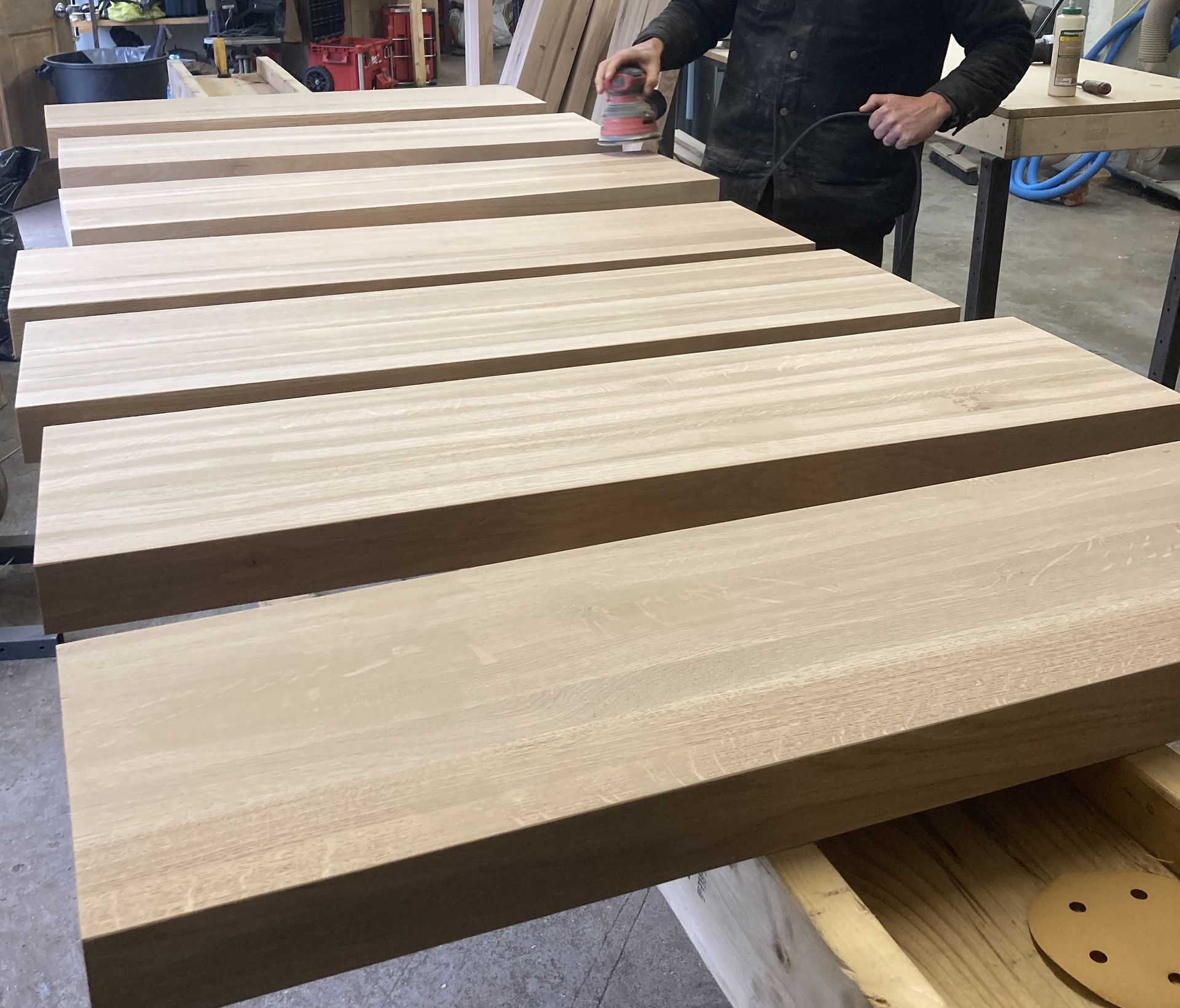 A man is sanding wooden boards in a workshop