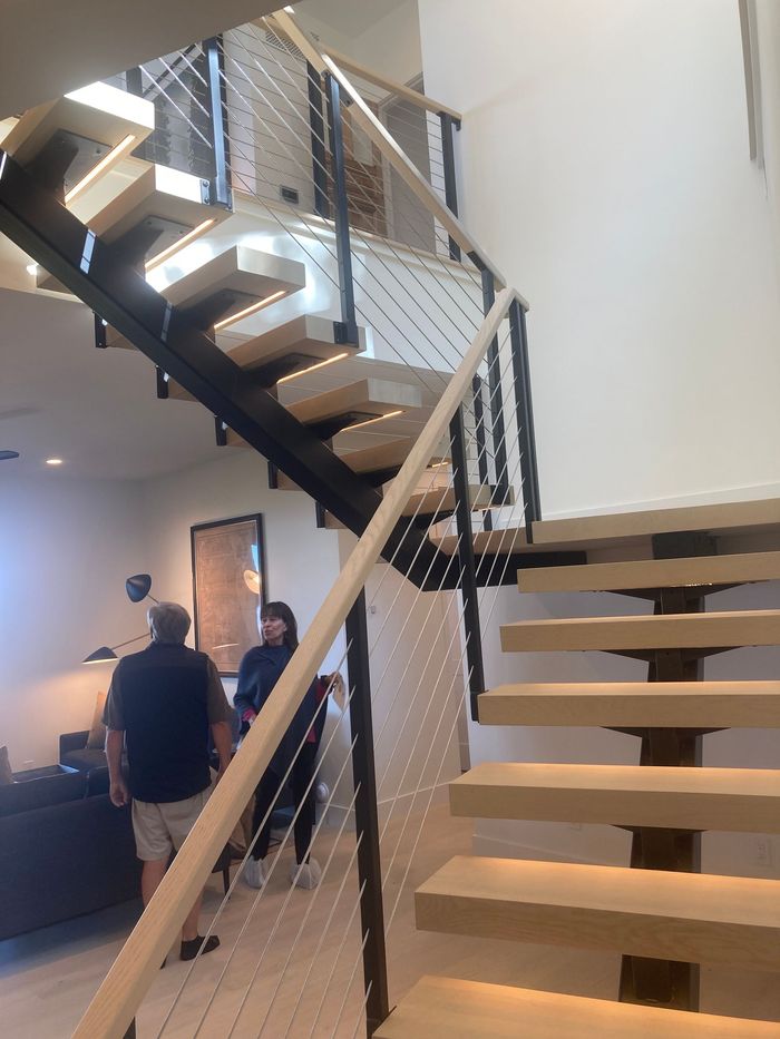 An aerial view of a wooden staircase with a black railing.