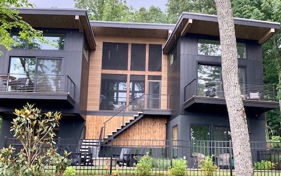 A large house with a lot of windows and balconies is surrounded by trees.