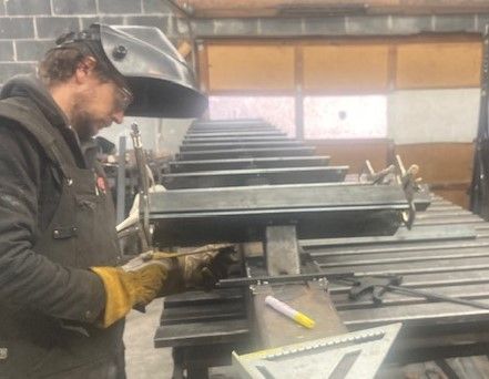 A man wearing a welding helmet is working on a piece of metal.