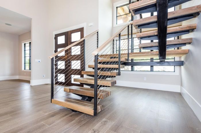 A kitchen with a wooden staircase leading up to the second floor.