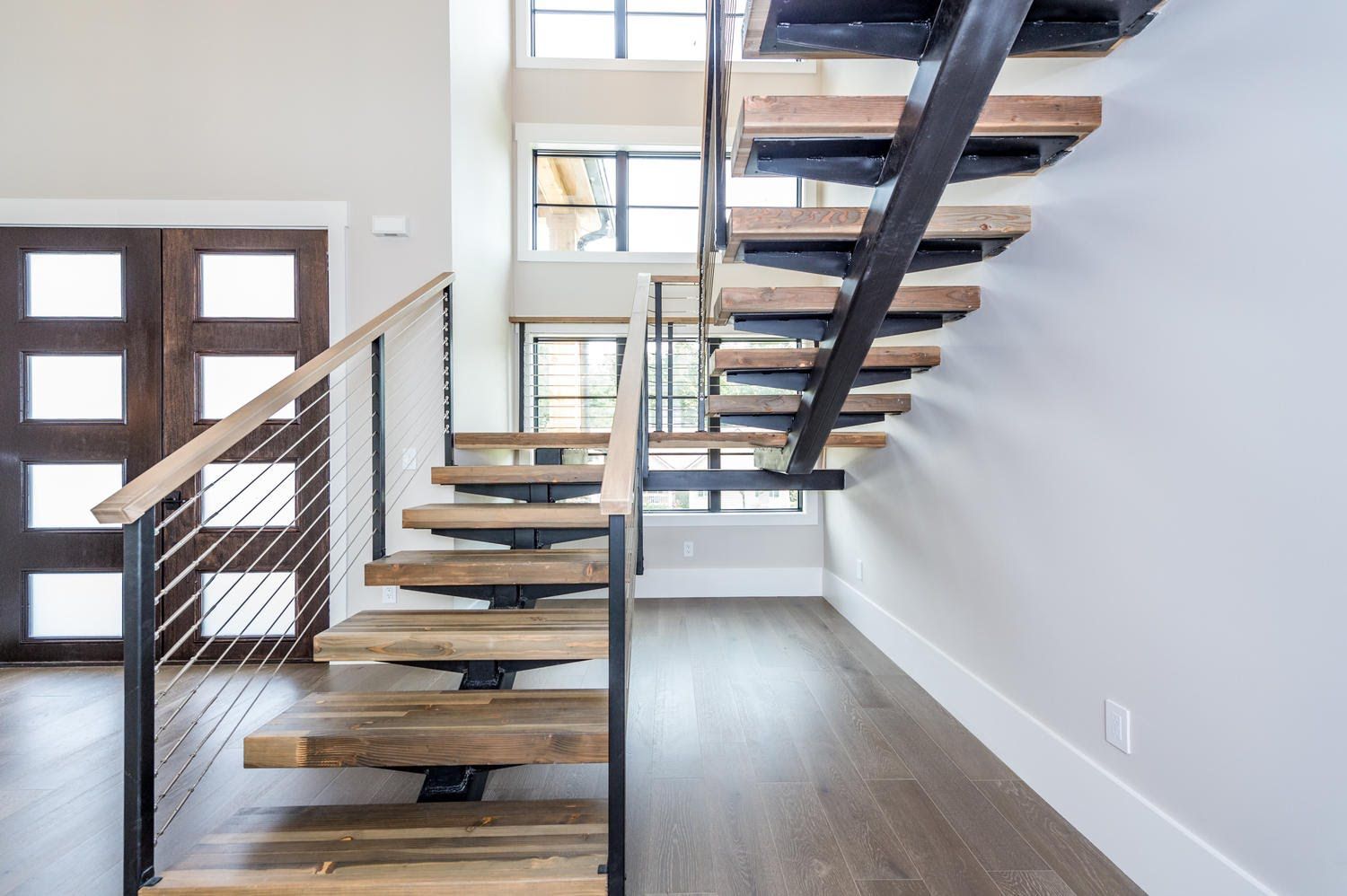 A wooden staircase with a metal railing is leading up to the second floor of a house.