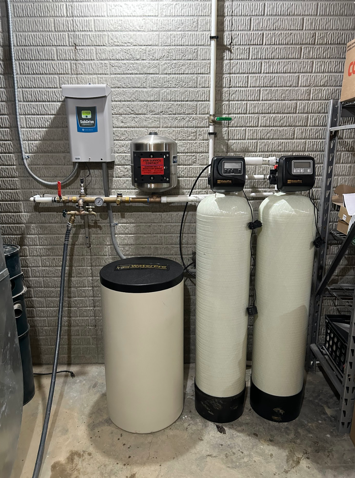 Water filtration system: Tanks, control panel, and softener in a brick-walled utility area.
