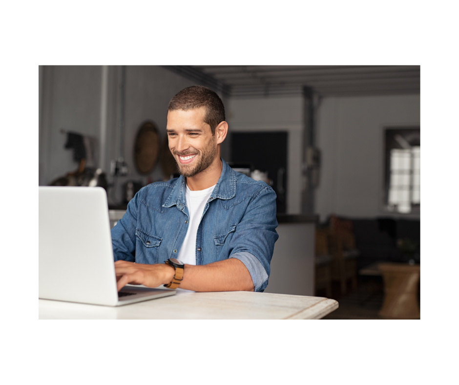 A man is sitting at a table using a laptop computer.