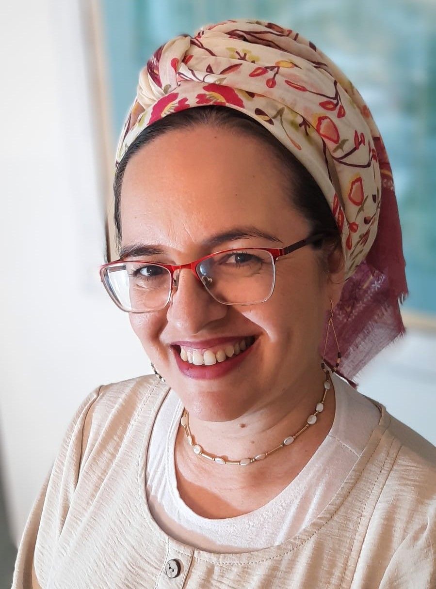 אישה עם משקפיים ומטפחת מחייכת.