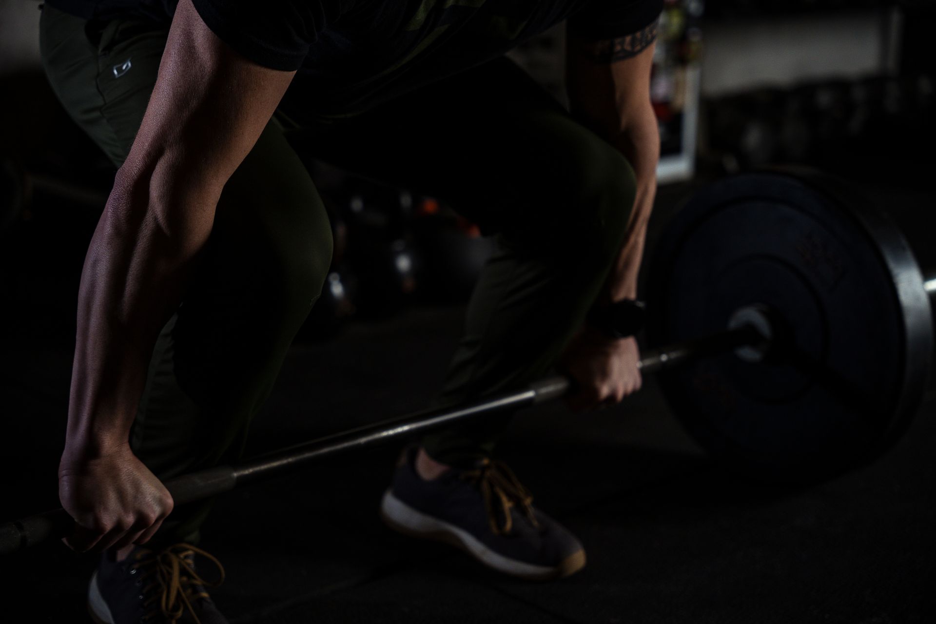 A man is lifting a barbell in a dark gym.