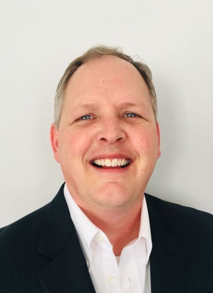 A man in a suit and white shirt is smiling for the camera