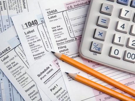 1040 tax forms and a calculator with two pencils