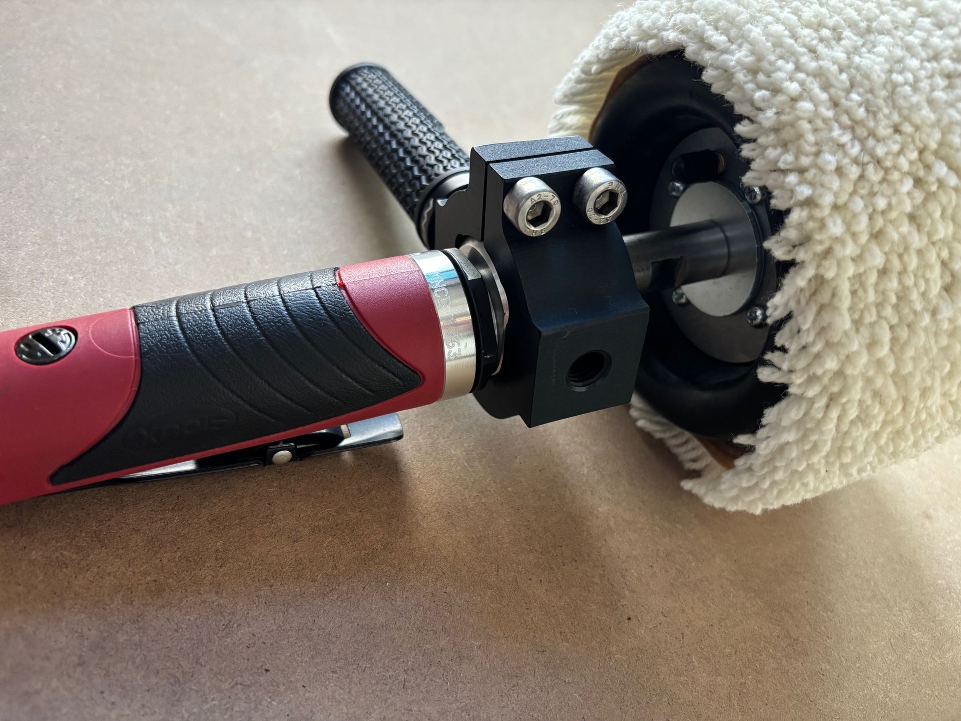 Red and black power tool with a white polishing pad attached.