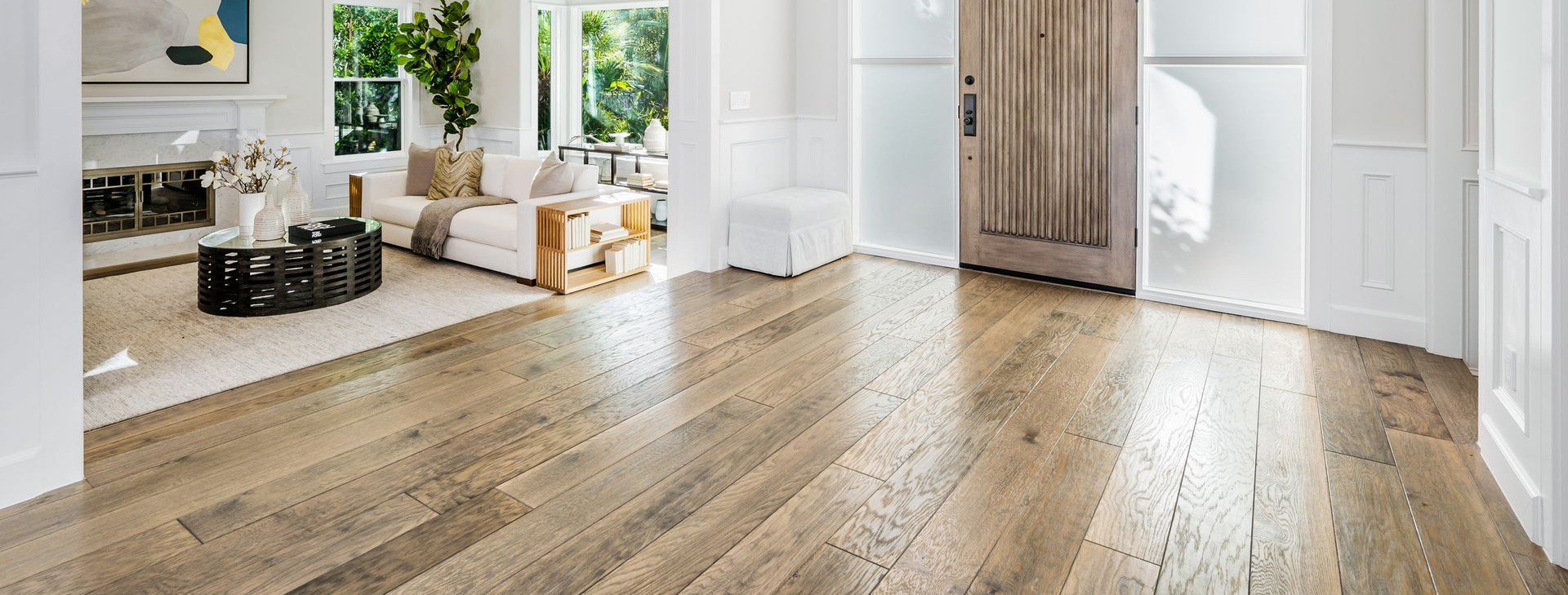 Empty room with herringbone wood floor, white walls, two windows, and hanging lights.