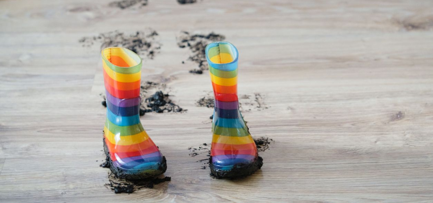 Girl smiling, lying on floor, with a dog resting beside her on a woven rug.