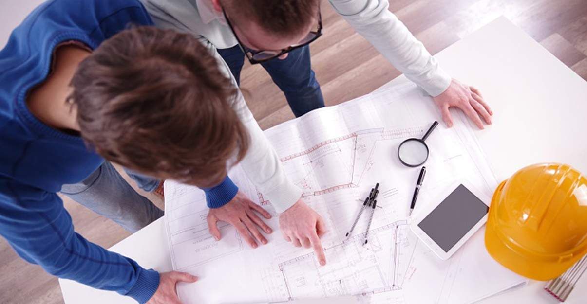 Deux hommes regardent un plan sur une table.