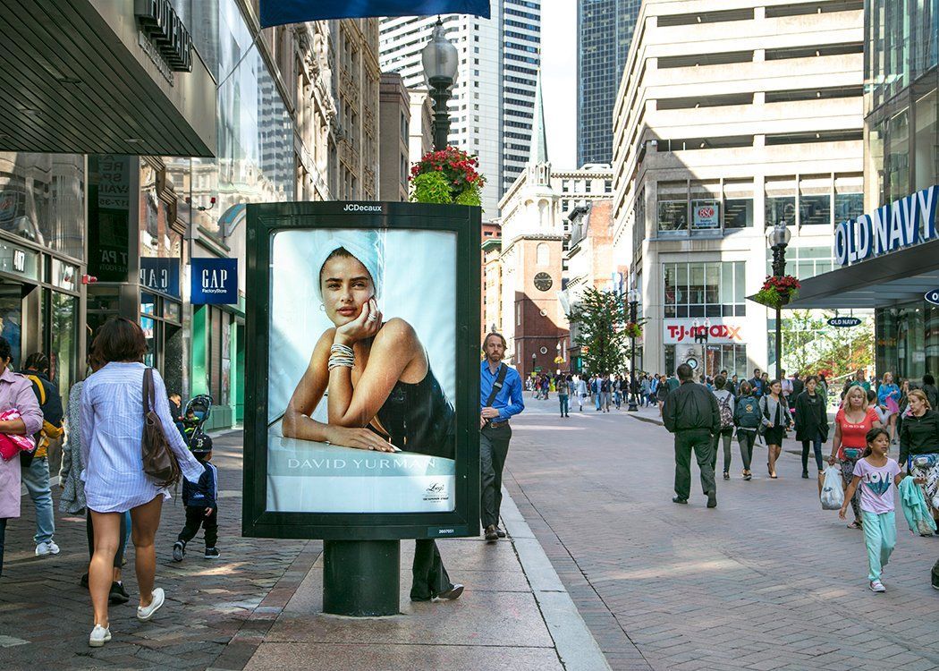 a woman is sitting in front of a billboard on a city street .