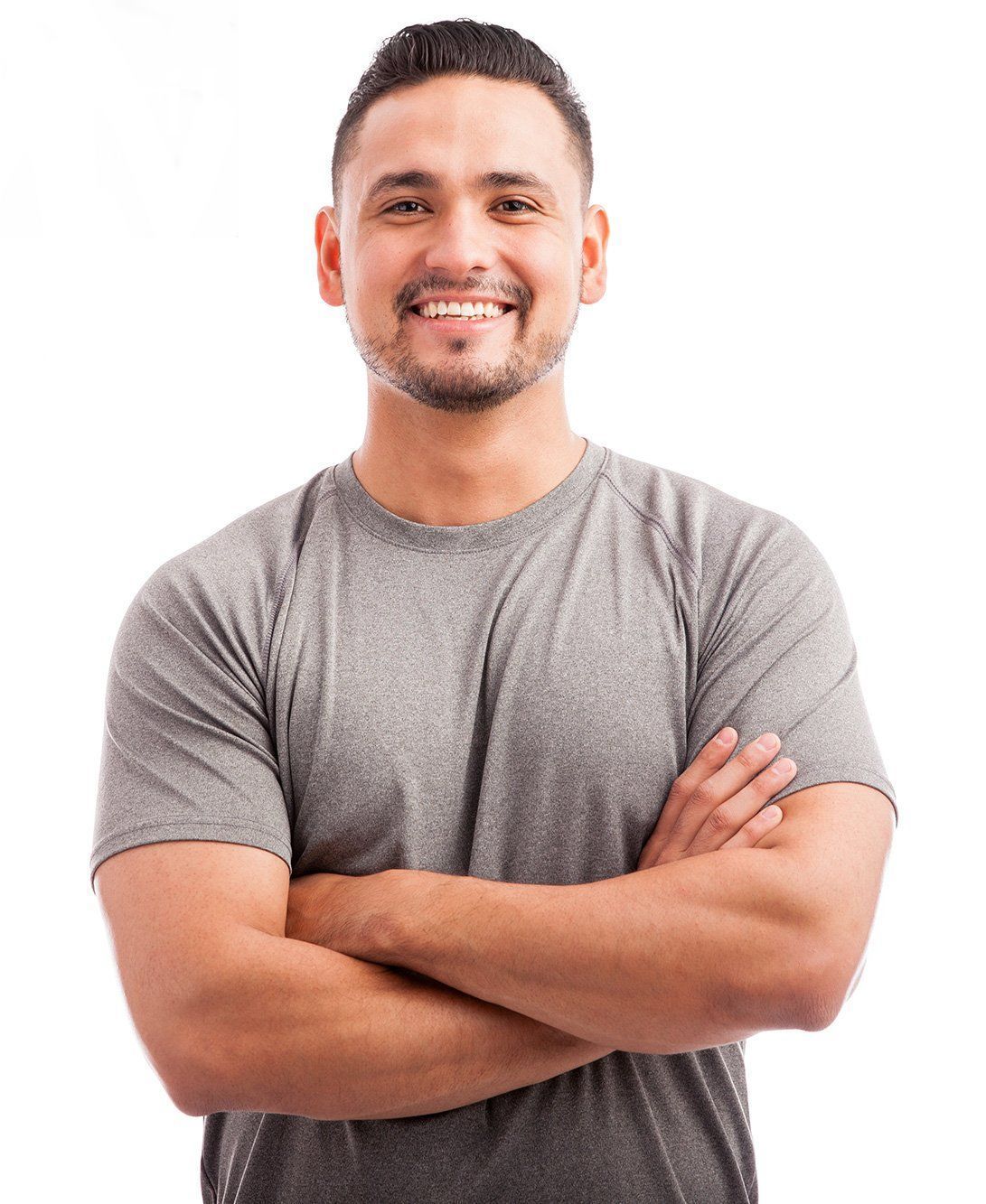 a man in a grey shirt is smiling with his arms crossed