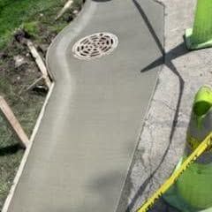 Newly poured concrete walkway with drain and safety cones. Newly poured concrete walkway with drain and safety cones.