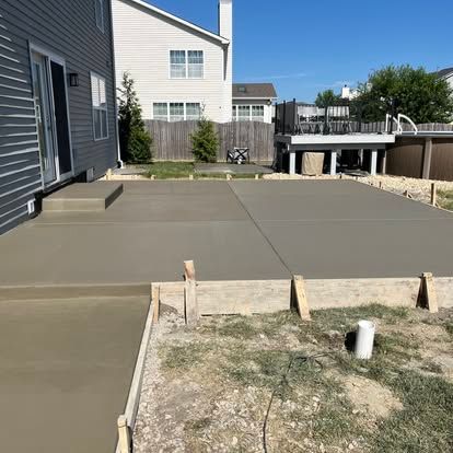 Newly poured concrete patio and walkway in a backyard, with wooden forms still in place. Newly poured concrete patio and walkway in a backyard, with wooden forms still in place.