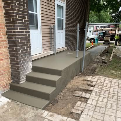 Newly poured concrete steps and landing outside a building.