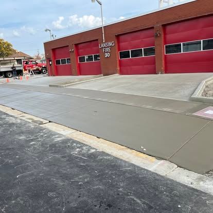 Fire station with red doors, fresh concrete sidewalk, and a truck parked outside. Fire station with red doors, fresh concrete sidewalk, and a truck parked outside.