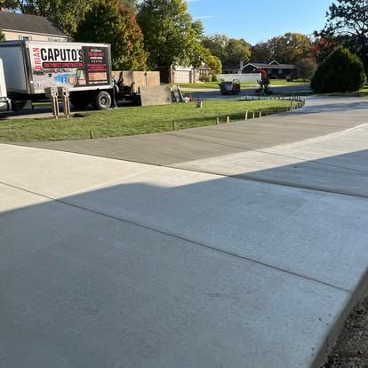Newly poured concrete driveway with a truck in the background, daytime. Newly poured concrete driveway with a truck in the background, daytime.