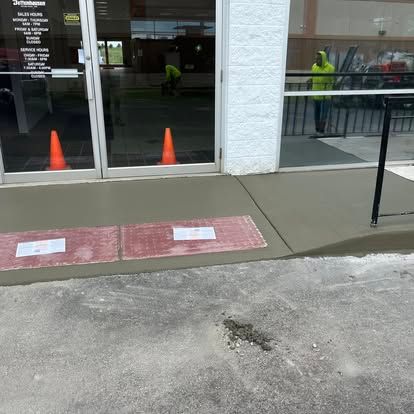 Newly poured concrete sidewalk with two orange cones near store entrance. Newly poured concrete sidewalk with two orange cones near store entrance.