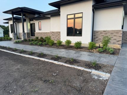 Modern house with landscaped beds, concrete walkway, and evening sky reflected in windows. Modern house with landscaped beds, concrete walkway, and evening sky reflected in windows.