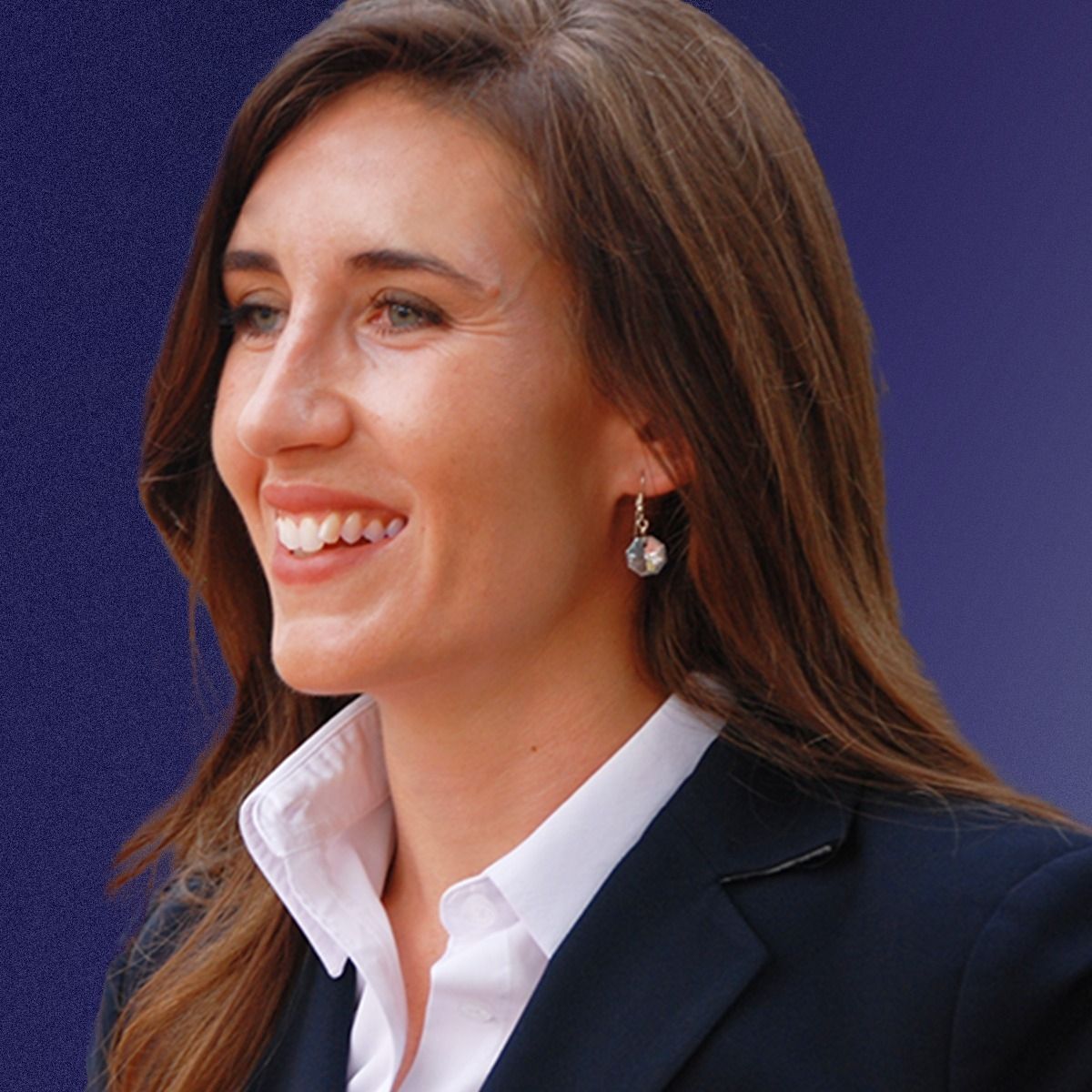 A woman wearing a suit and earrings is smiling