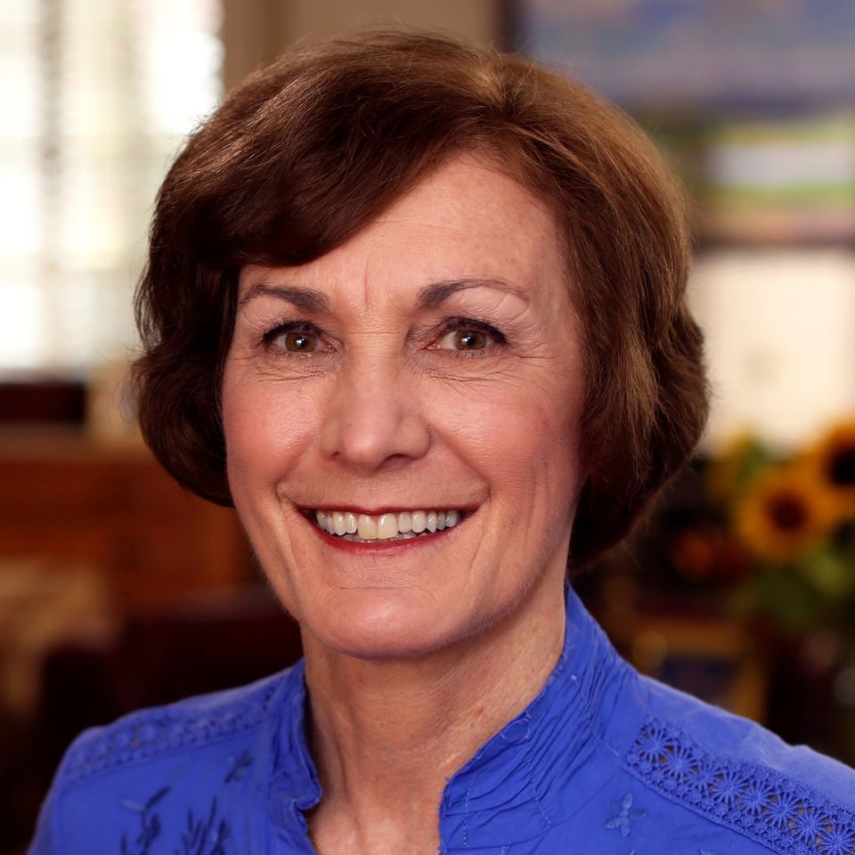 A woman in a blue shirt is smiling for the camera.