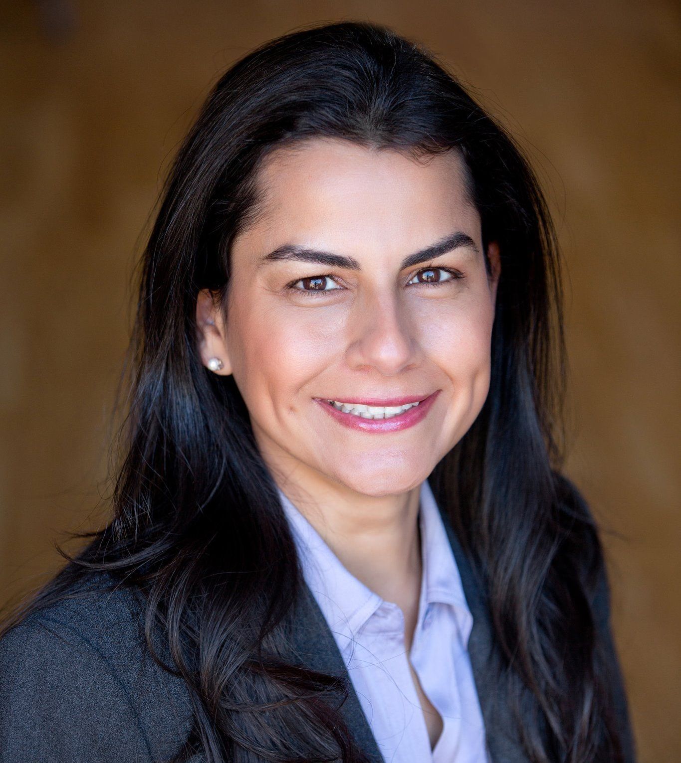 A woman in a suit and a purple shirt is smiling for the camera.