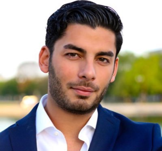 A man with a beard wearing a blue suit and white shirt