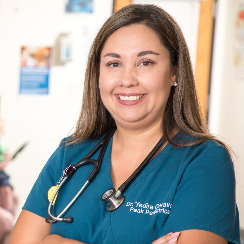 A woman wearing a blue scrub top with a stethoscope around her neck