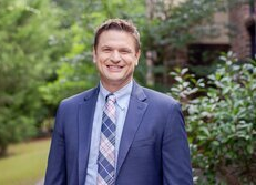 A man in a suit and tie is smiling for the camera.