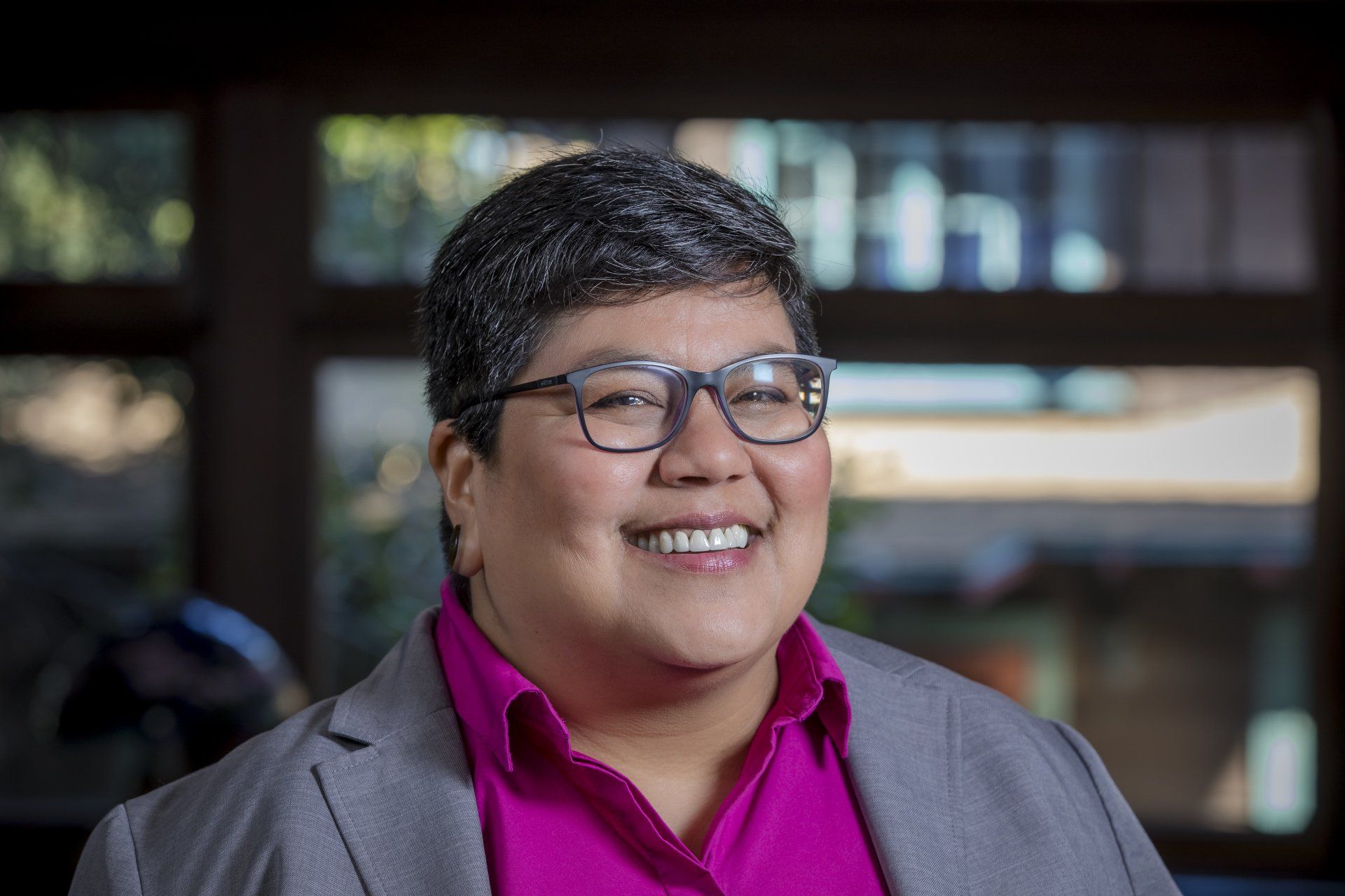 A woman wearing glasses and a purple shirt is smiling for the camera.