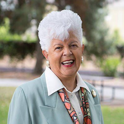 A woman in a suit and scarf is smiling for the camera.