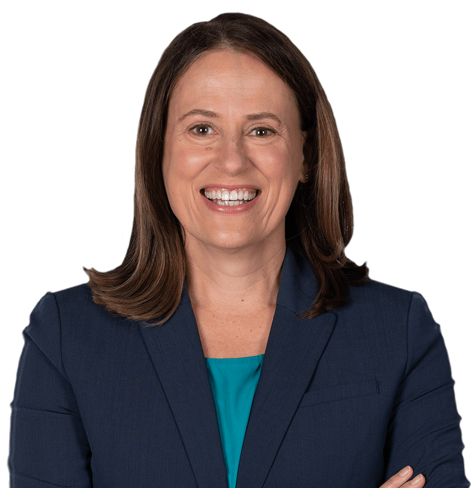 A woman in a blue jacket is smiling with her arms crossed