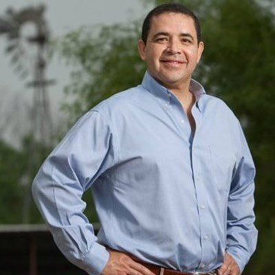 A man in a blue shirt is standing with his hands on his hips.